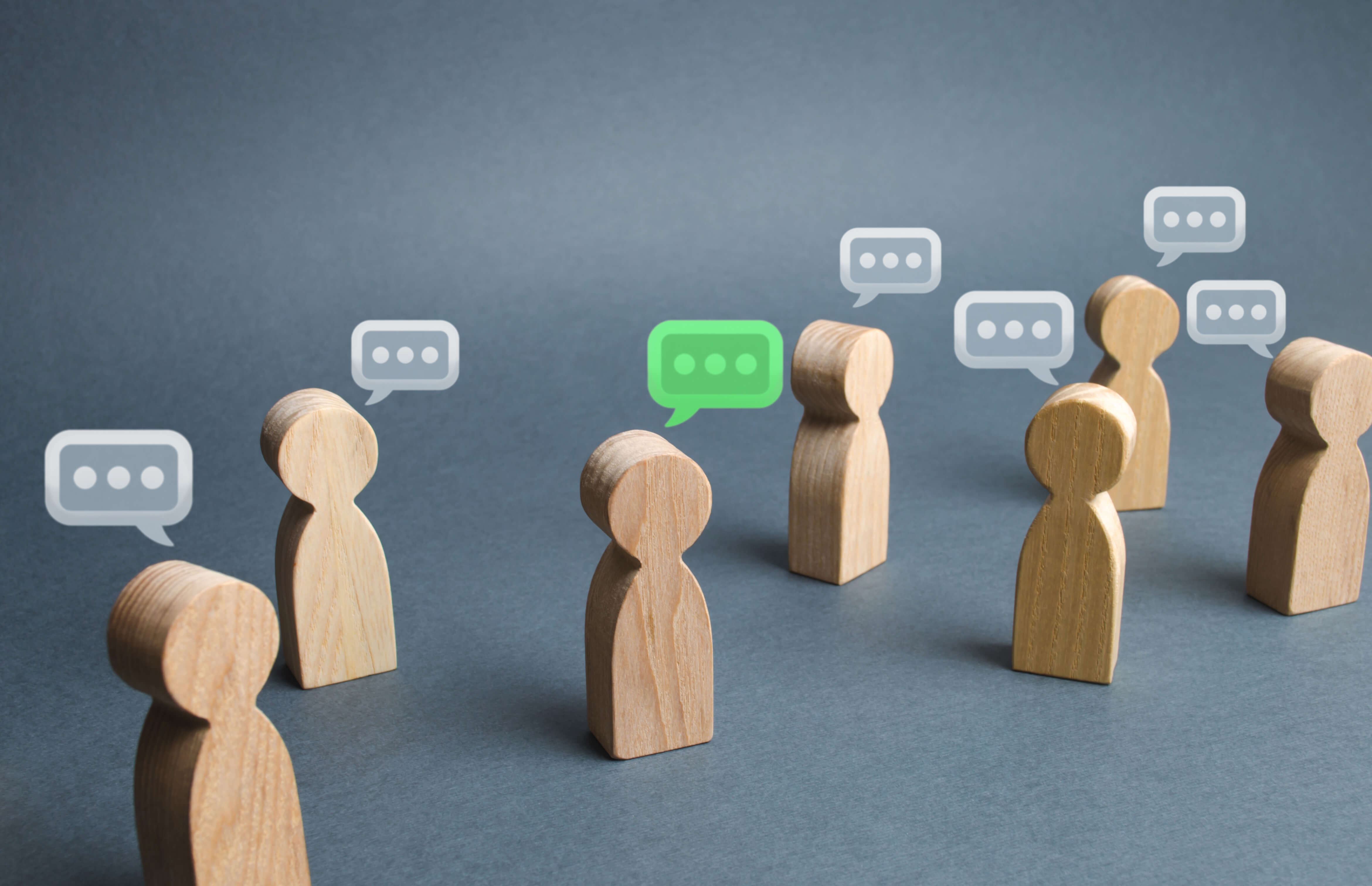Image shows wooden blocks shaped like people, each with a speech bubble above their head.