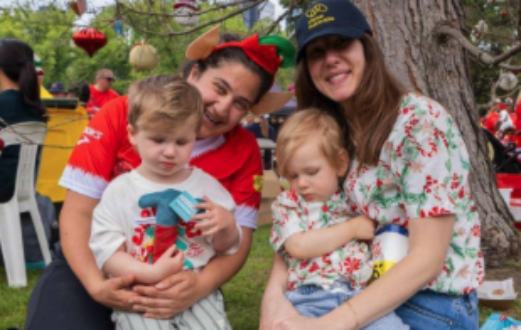 2 women holding 2 small children at an event for Vision Australia peer groups