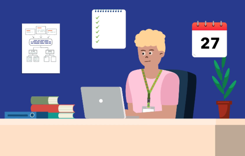 Man sitting at a desk with a computer and on the wall behind him is a planner, a checklist and a calendar