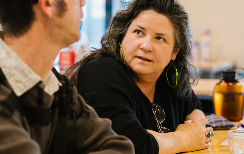 Woman with a concerned look on her face is leaning on a counter talking to a man